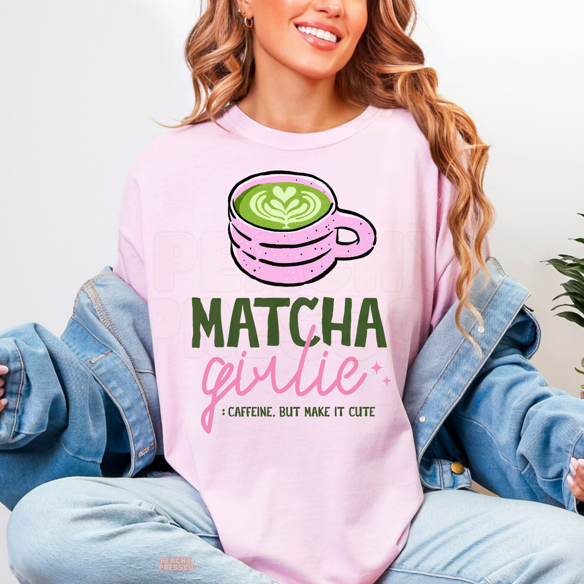 Light pink Matcha Girlie shirt featuring a pink matcha latte cup with green heart latte art, bold Matcha Girlie lettering, and caffeine quote.