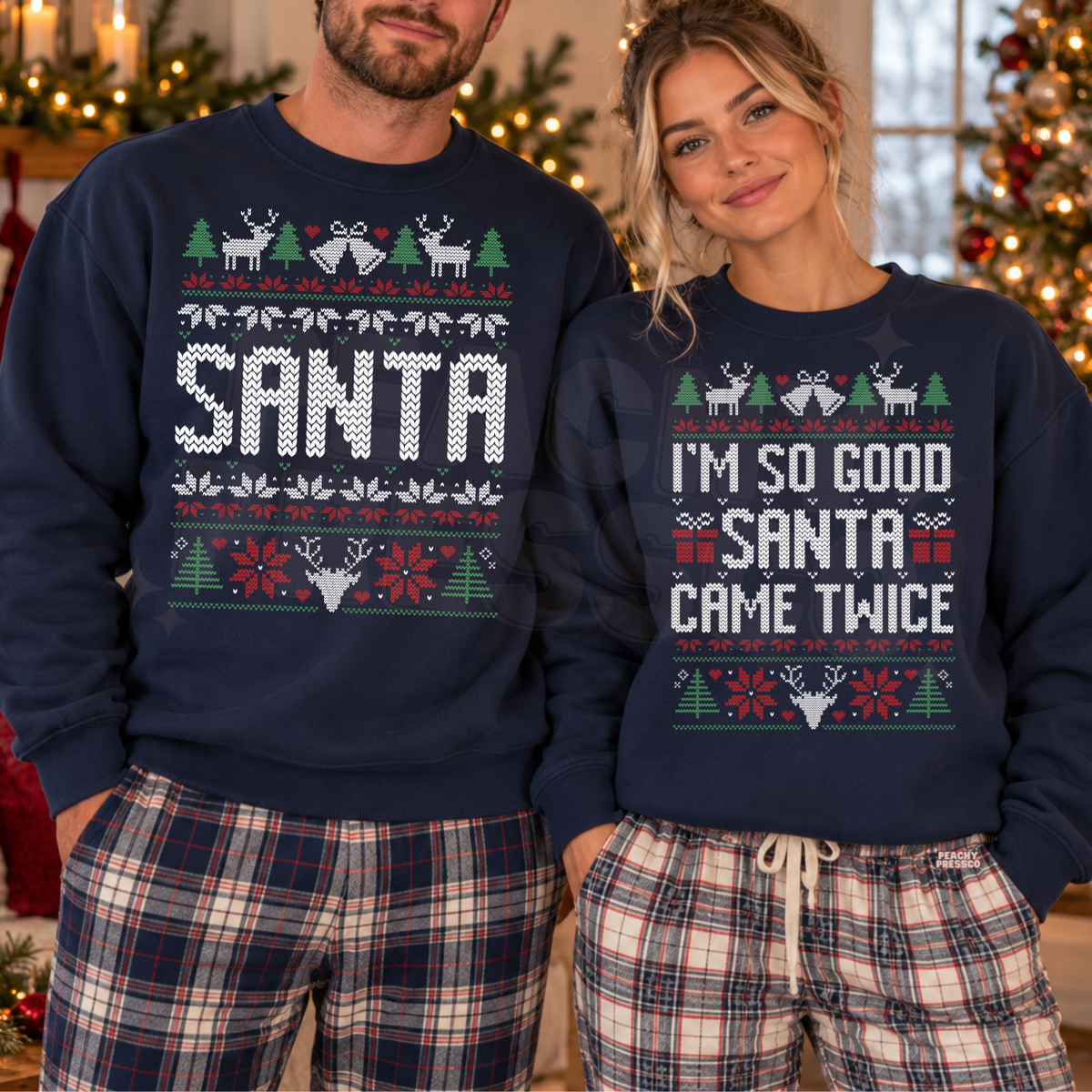 A man and a woman wearing matching navy blue Christmas sweaters with holiday graphics. The man's sweater says 'SANTA' in large white letters, and the woman's says 'I'M SO GOOD SANTA CAME TWICE'.