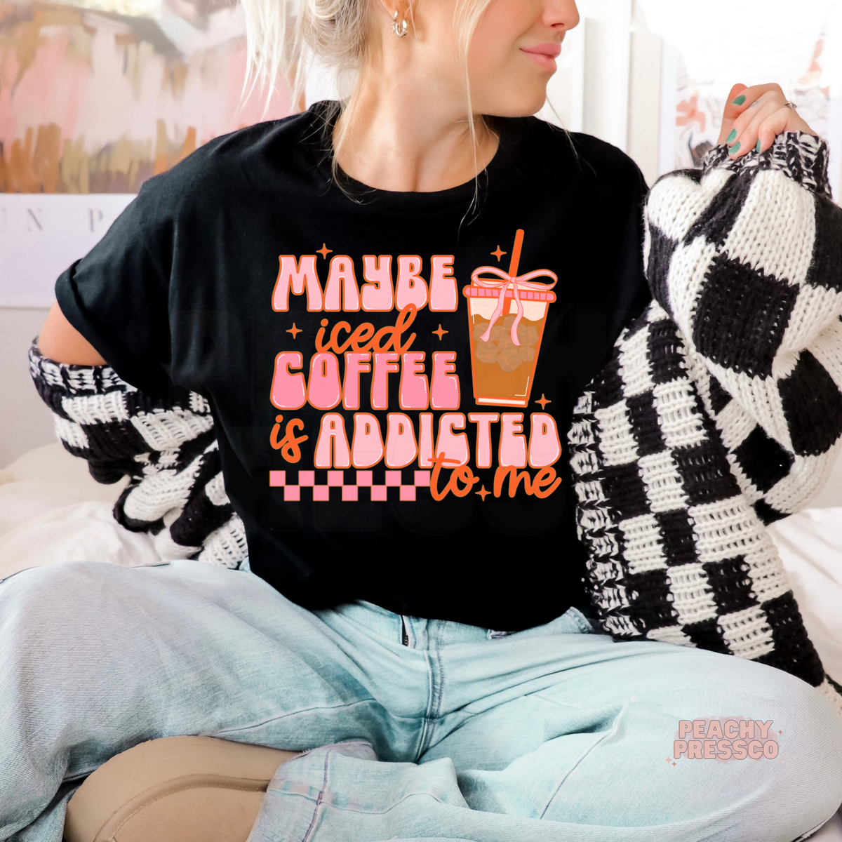 Black graphic t-shirt with the humorous "Maybe Iced Coffee Is Addicted to Me" quote and colorful iced coffee cup design.