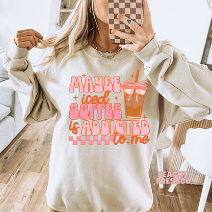 Sand beige crewneck sweatshirt with the humorous "Maybe Iced Coffee Is Addicted to Me" graphic and iced coffee cup illustration.