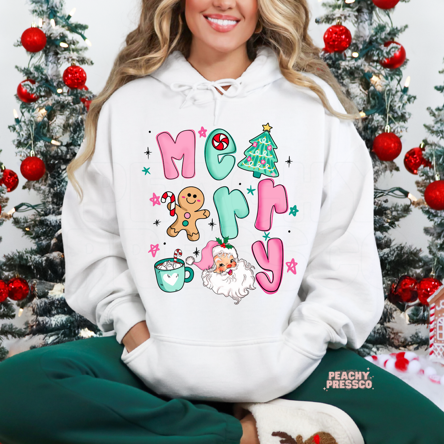 Woman wearing a white Christmas hoodie featuring a colorful Merry Christmas design with Santa, gingerbread man, Christmas tree and holiday mug.