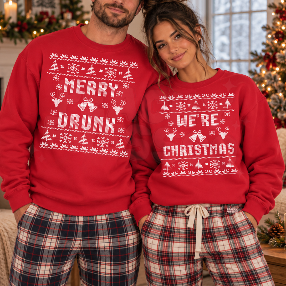 A man and a woman wearing matching red Christmas sweatpants with white holiday graphics and text. The man's sweatshirt says 'MERRY DRUNK' and the woman's says 'WE'RE CHRISTMAS'.