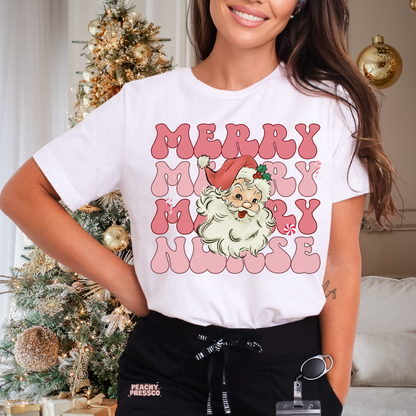 A woman wearing a white graphic t-shirt with a pink and green 'Merry Merry Merry Nurse' Santa Claus design, paired with black drawstring pants in a decorated holiday home setting.
