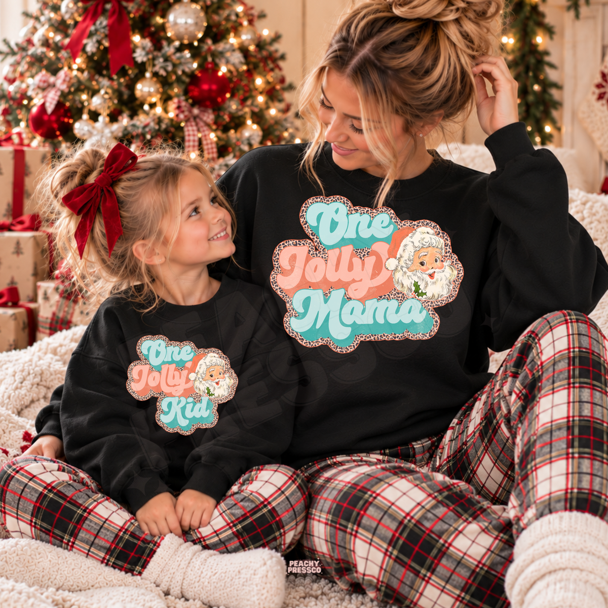 Mom and child wearing matching black One Jolly Mama and One Jolly Kid Christmas sweatshirts with retro Santa design.