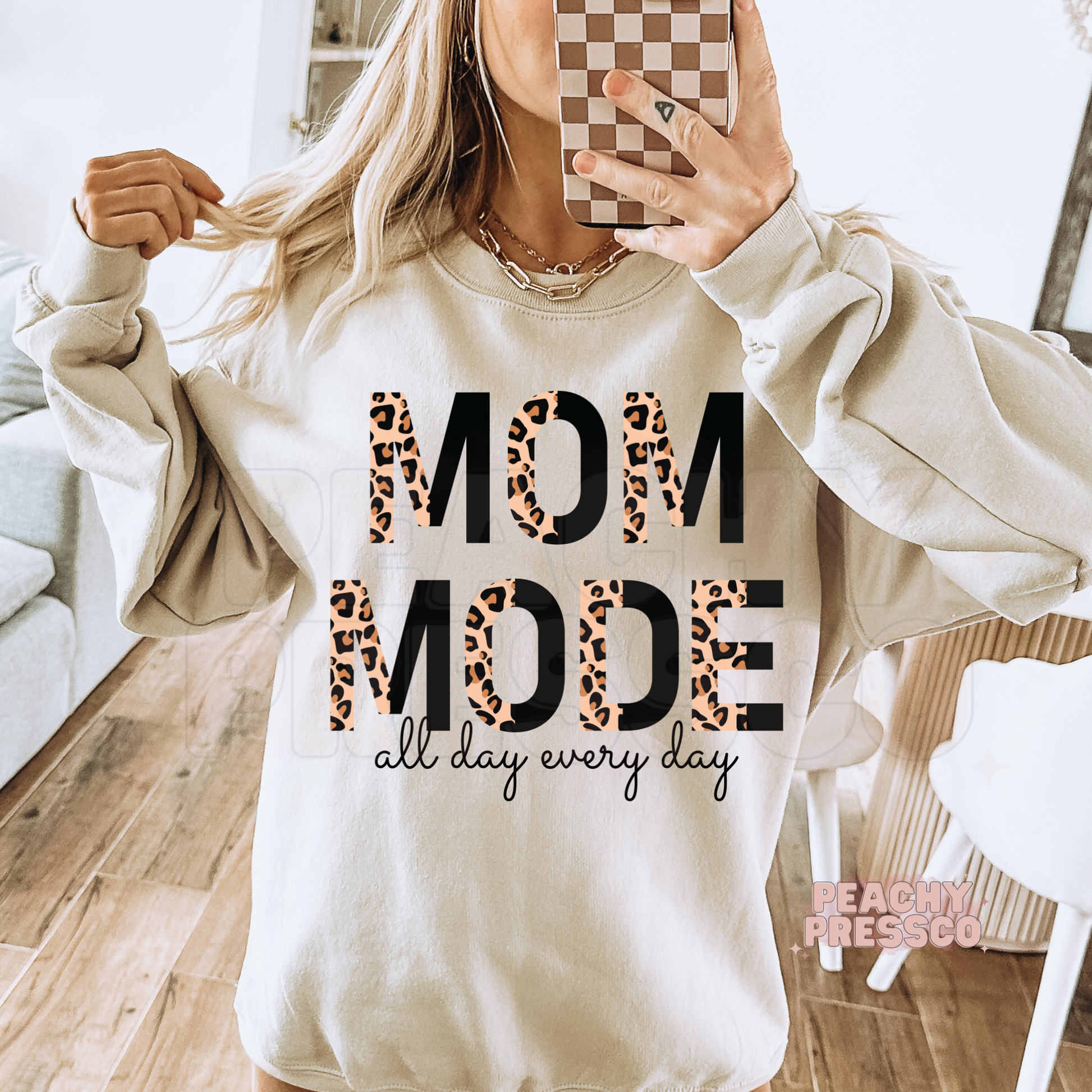 Sand sweatshirt featuring a trendy "Mom Mode All Day Every Day" leopard print graphic with modern typography. Cozy gift for moms.
