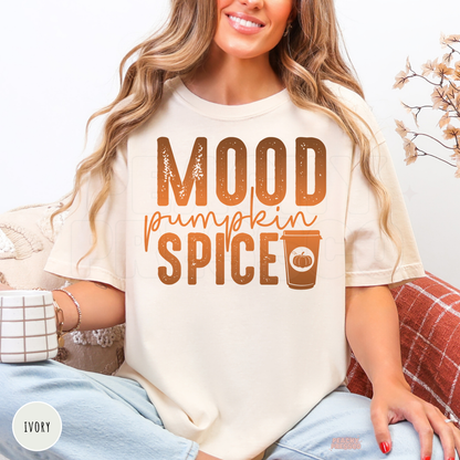 Woman wearing an ivory Comfort Colors t-shirt featuring a "Mood Pumpkin Spice" graphic with a pumpkin spice coffee cup in warm autumn colors.