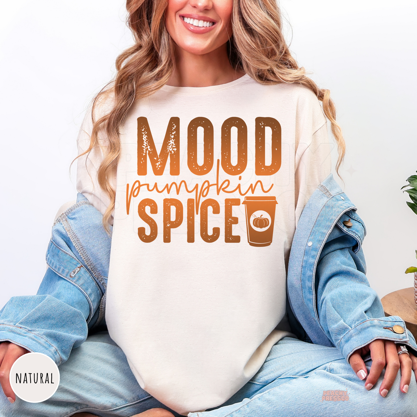 Woman wearing a natural t-shirt with a bold "Mood Pumpkin Spice" fall graphic and pumpkin spice coffee cup design.