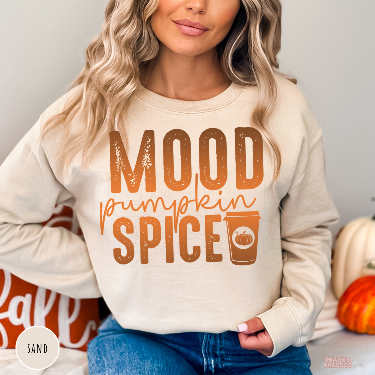 Woman wearing a sand crewneck sweatshirt featuring a distressed "Mood Pumpkin Spice" graphic with a pumpkin spice coffee cup.
