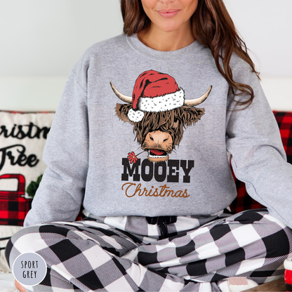 Women wearing a sport grey Mooey Christmas highland cow crewneck sweater paired with black and white buffalo plaid pajama pants.