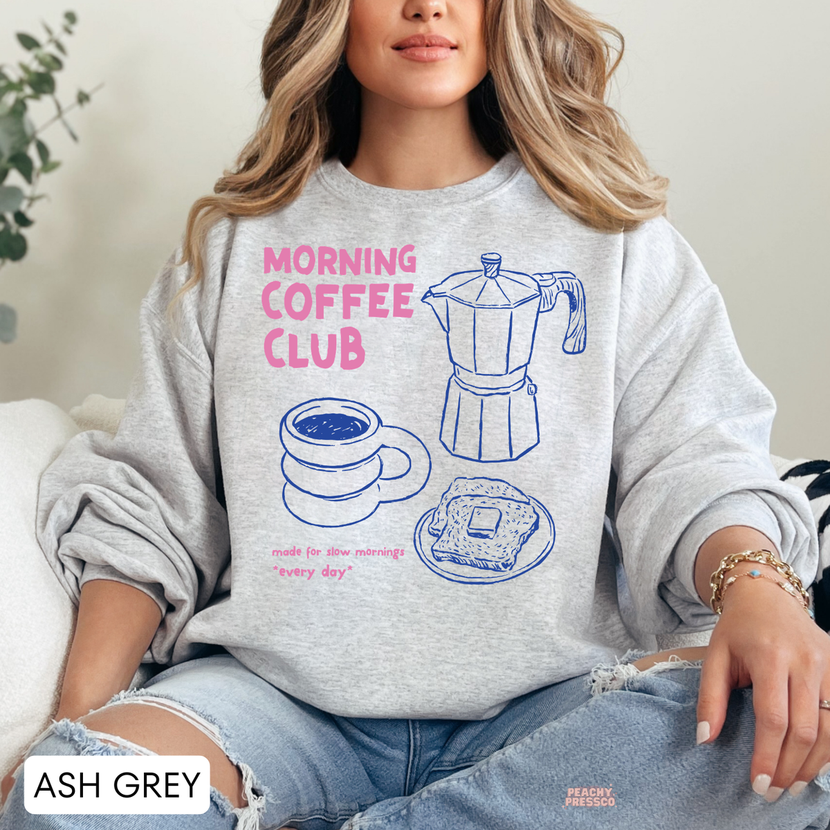 Ash grey Morning Coffee Club sweatshirt featuring pink typography, blue coffee maker, coffee cup and breakfast toast illustrations.