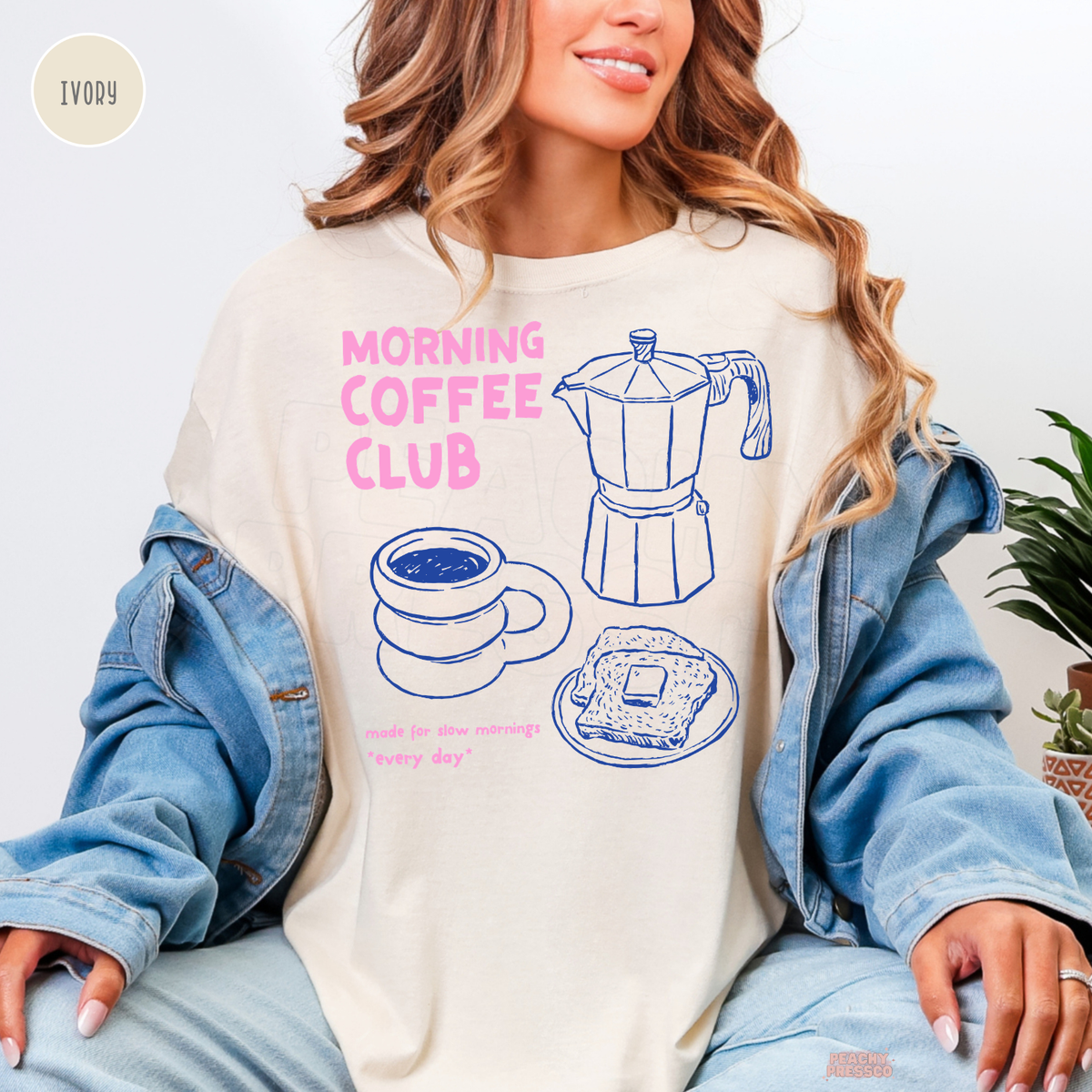 Ivory Morning Coffee Club Comfort Colors shirt with pink lettering, blue moka pot illustration, stacked coffee cup and buttered toast design.