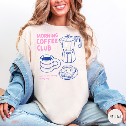 Natural Morning Coffee Club shirt featuring pink lettering, blue moka pot, coffee cup and buttered toast illustrations with a cozy morning theme.