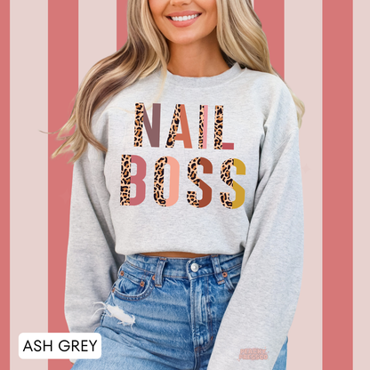 Woman wearing an ash grey Nail Boss crewneck sweatshirt featuring colorful leopard print lettering, a fun design for nail technicians.