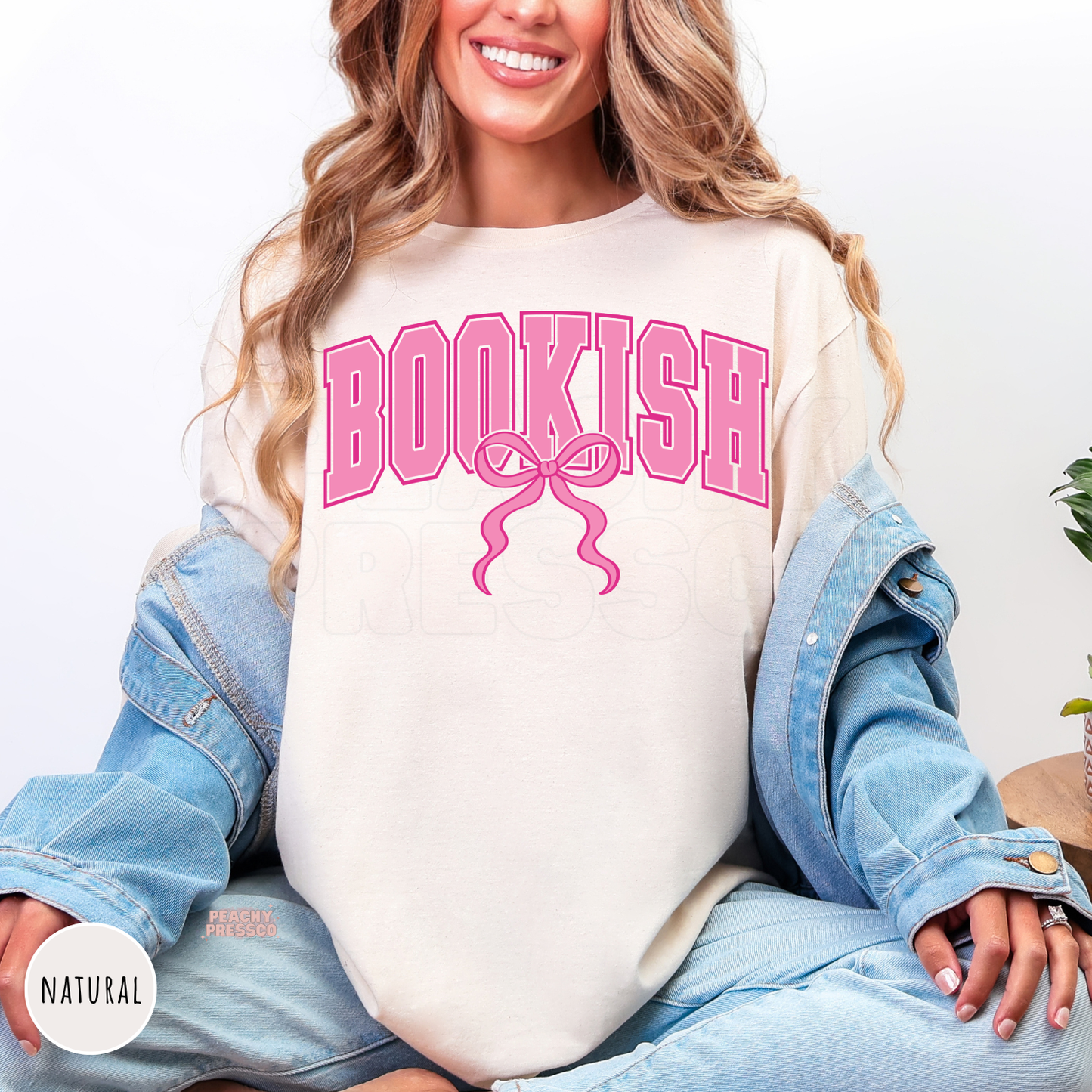 Natural cream tee featuring a pink varsity "Bookish" graphic with a coquette bow, cozy aesthetic shirt for book lovers and readers.