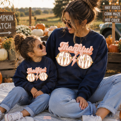 Mama and mini wearing matching navy Thankful Mama sweatshirts with pumpkin patch decor, ideal for autumn outings and Thanksgiving celebrations.