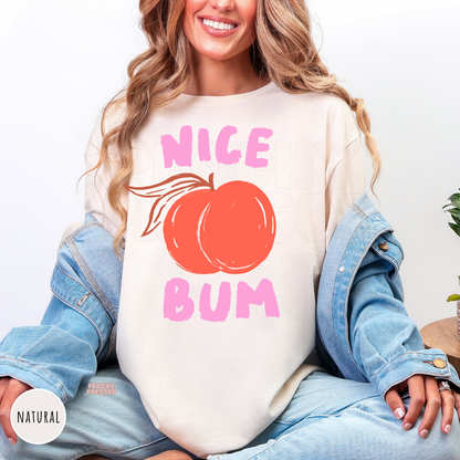 Natural crewneck shirt featuring a fun "Nice Bum" peach graphic in pink and coral with a vintage-inspired design for casual fall and summer wear.