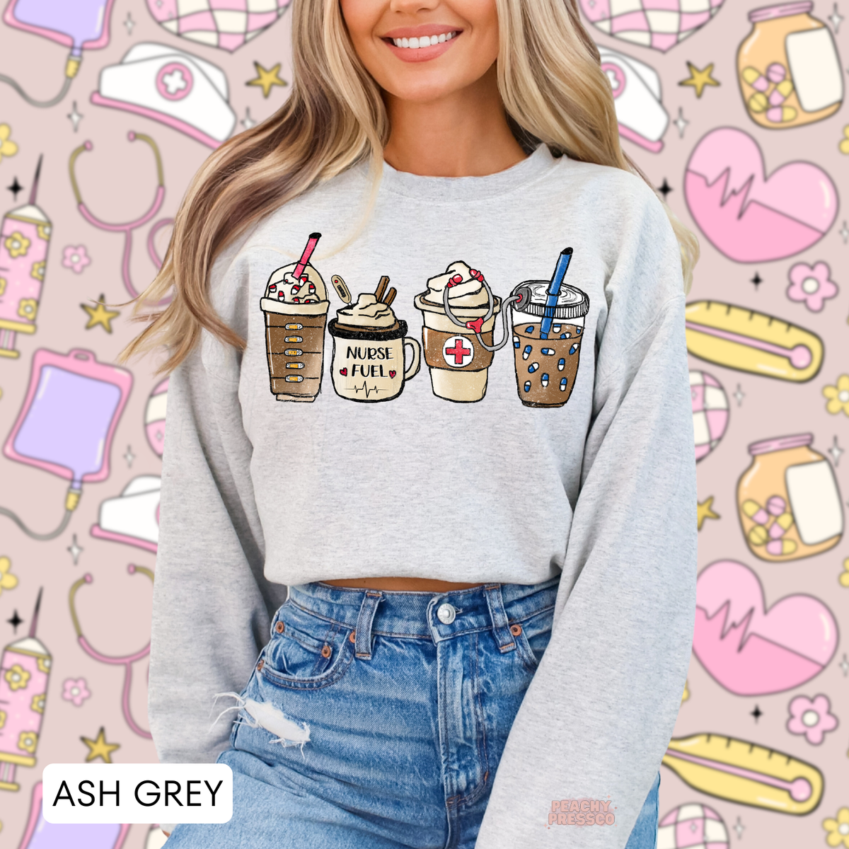 Ash grey Nurse Fuel sweatshirt featuring four illustrated coffee drinks, a medical cross, stethoscope and cute nursing details, styled with blue jeans.