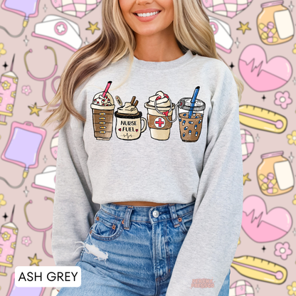 Ash grey Nurse Fuel sweatshirt featuring four illustrated coffee drinks, a medical cross, stethoscope and cute nursing details, styled with blue jeans.