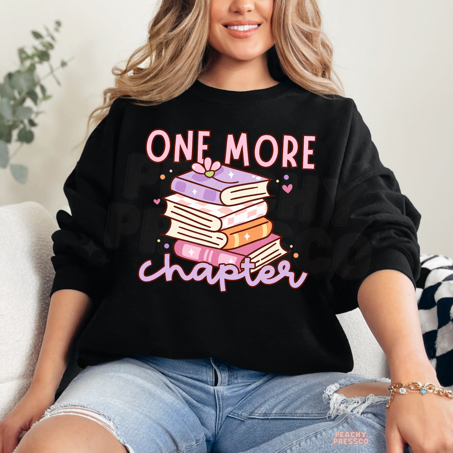 Black crewneck sweatshirt with a colorful stack of books and "One More Chapter" design, a perfect gift for avid readers.