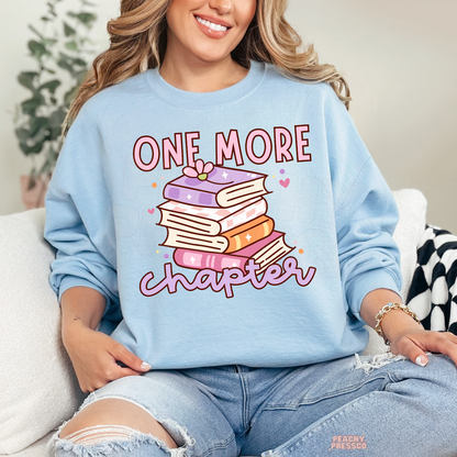 Light blue crewneck sweatshirt with a pastel stack of books and "One More Chapter" graphic, perfect for cozy reading outfits.