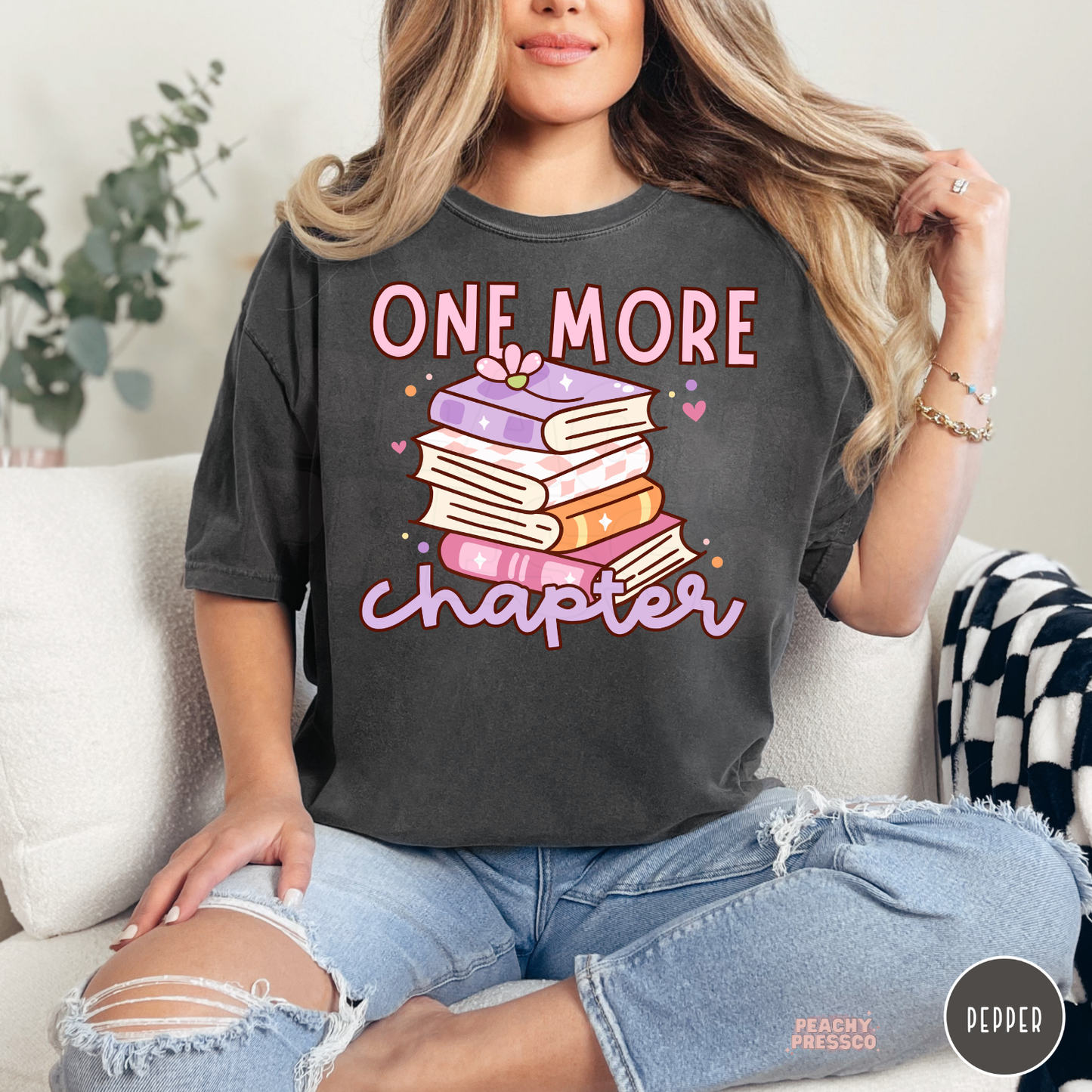 Pepper Comfort Colors tee featuring a colorful stack of books with the phrase "One More Chapter" for bookworms and reading enthusiasts.