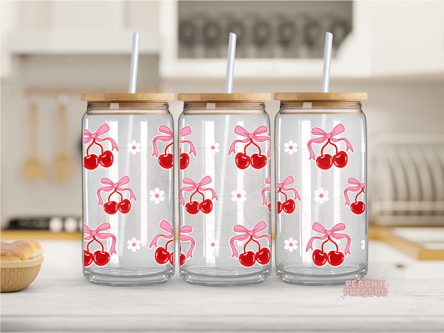 16 oz glass cup featuring a repeating pattern of red cherries tied with pink bows and tiny white flowers, complete with a bamboo lid and glass straw.