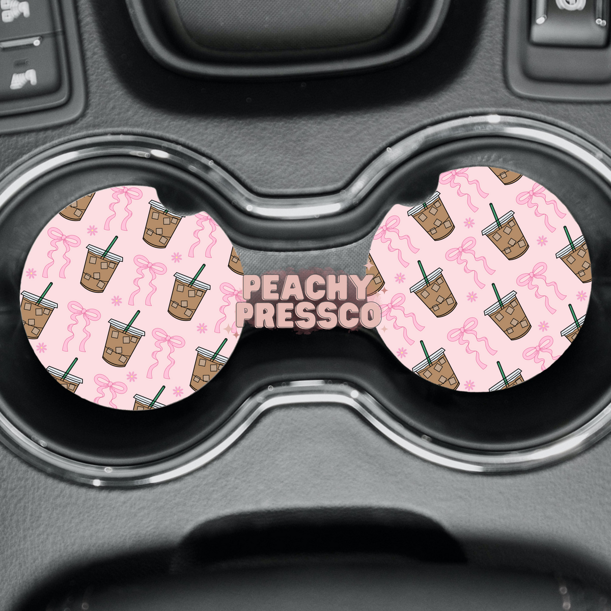 Pink bow and iced coffee ceramic car coasters displayed in vehicle cup holders.