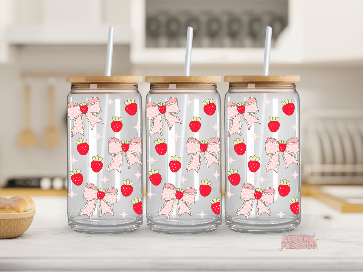 16 oz glass cup featuring a repeating pattern of pink bows, strawberries, and soft pink stars with a bamboo lid and reusable glass straw.
