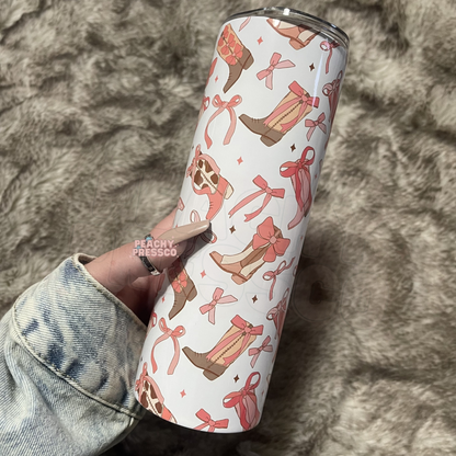 Pink western tumbler featuring cowgirl boots, bows, ribbons, and feminine western pattern design.