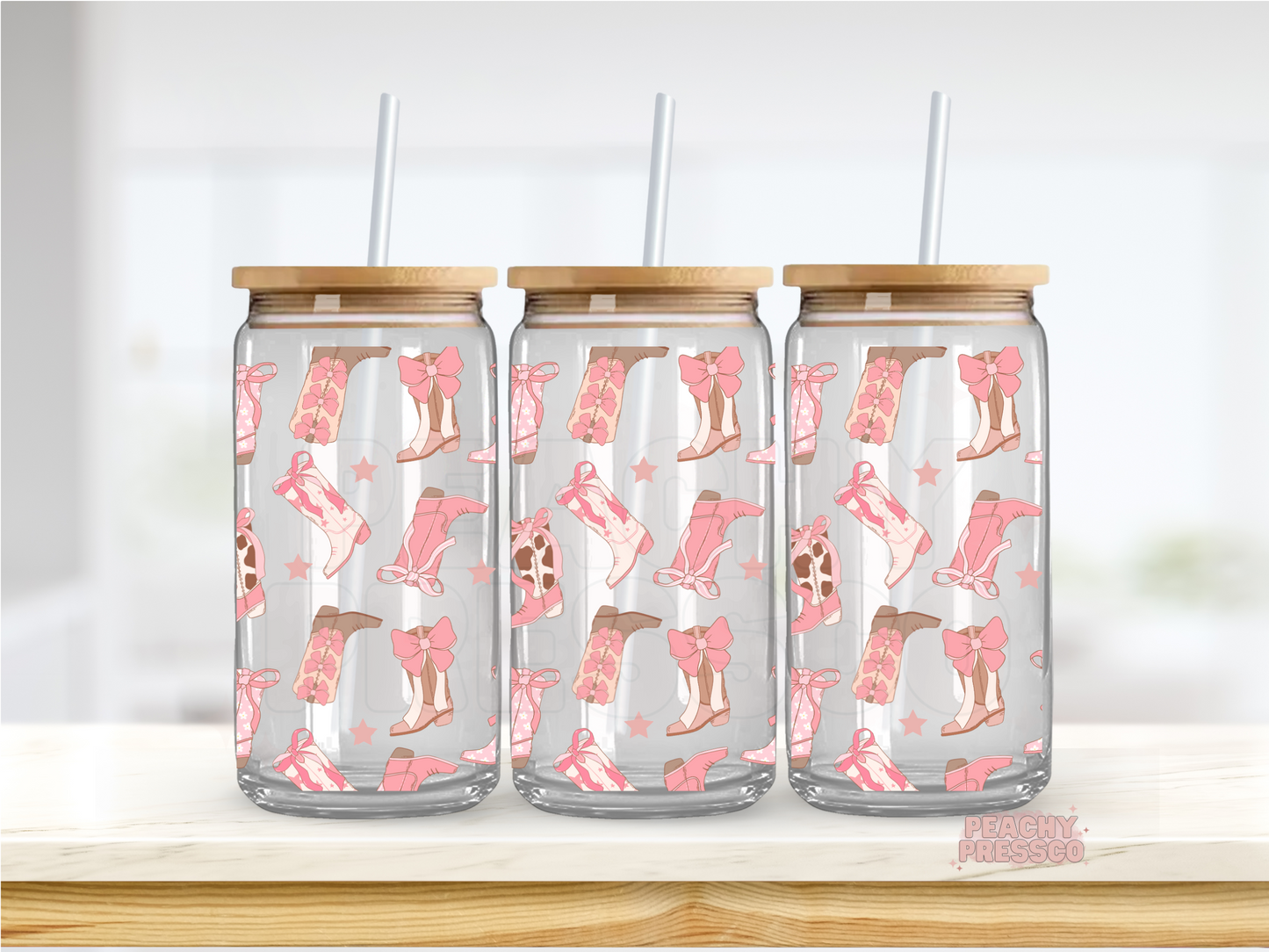 16oz glass cup decorated with pink cowgirl boots, bows, stars, and western-inspired illustrations. Includes bamboo lid and reusable glass straw.