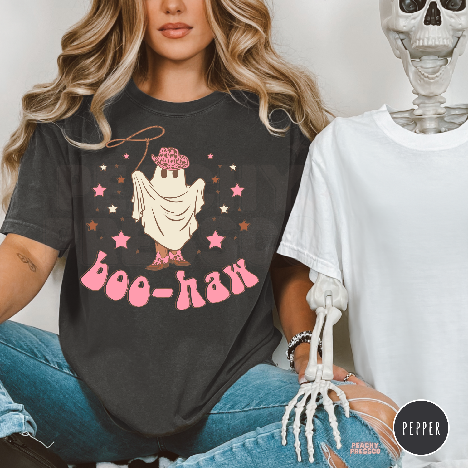 Woman wearing a pepper Comfort Colors Halloween t-shirt featuring a cute cowgirl ghost with pink cowboy hat, lasso and Boo-Haw graphic.