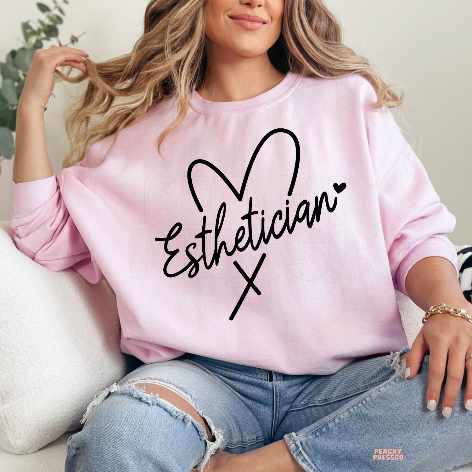 Soft pink crewneck sweatshirt featuring a black Esthetician heart script design, a thoughtful gift for estheticians, beauty professionals, and skincare lovers.