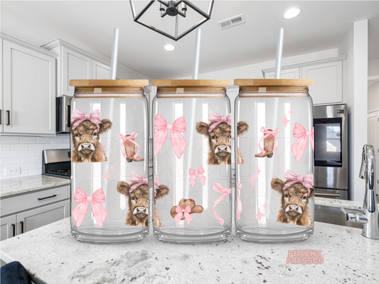 16oz glass cup featuring adorable Highland cows with pink bows, cowgirl boots, hats, and ribbons. Includes a bamboo lid and reusable glass straw, perfect for iced coffee lovers and western cowgirl gifts.