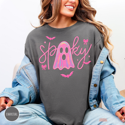 Woman wearing a charcoal crewneck sweatshirt featuring a pink spooky ghost graphic with holographic ghost and cute Halloween bats.
