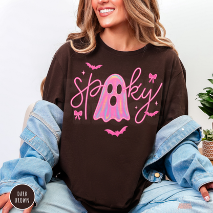 Woman wearing a dark brown crewneck sweatshirt featuring a trendy pink spooky ghost Halloween design with bows and bats.