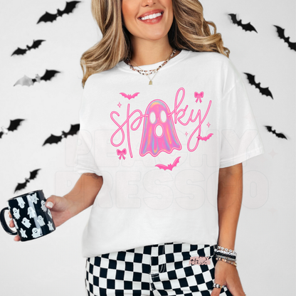 Woman wearing a white t-shirt featuring a cute pink spooky ghost graphic with holographic ghost, bows and bats for spooky season.