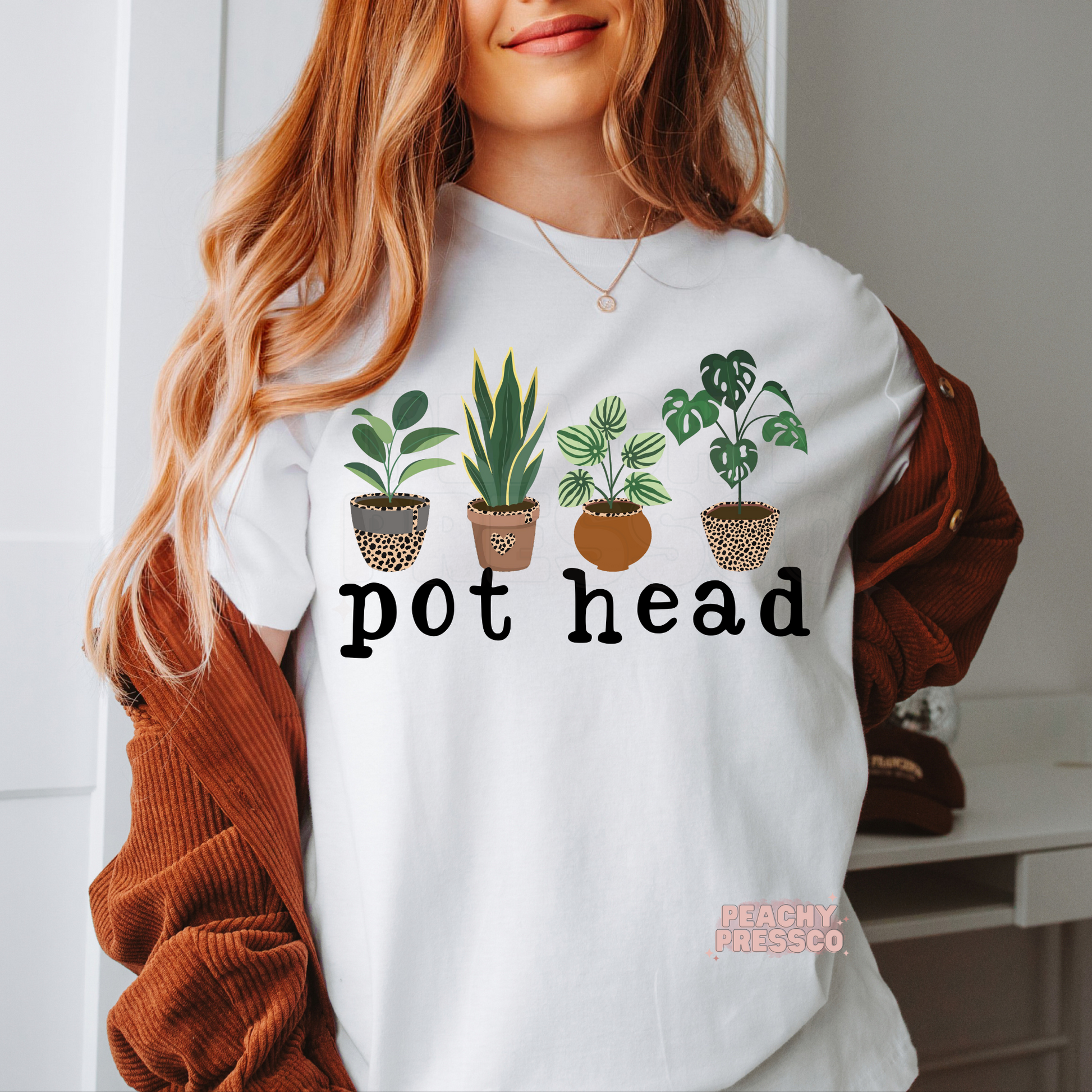 White unisex t-shirt featuring a playful "Pot Head" design with four illustrated potted houseplants and bold black lettering. Funny botanical tee for plant lovers, gardeners, and gift giving.