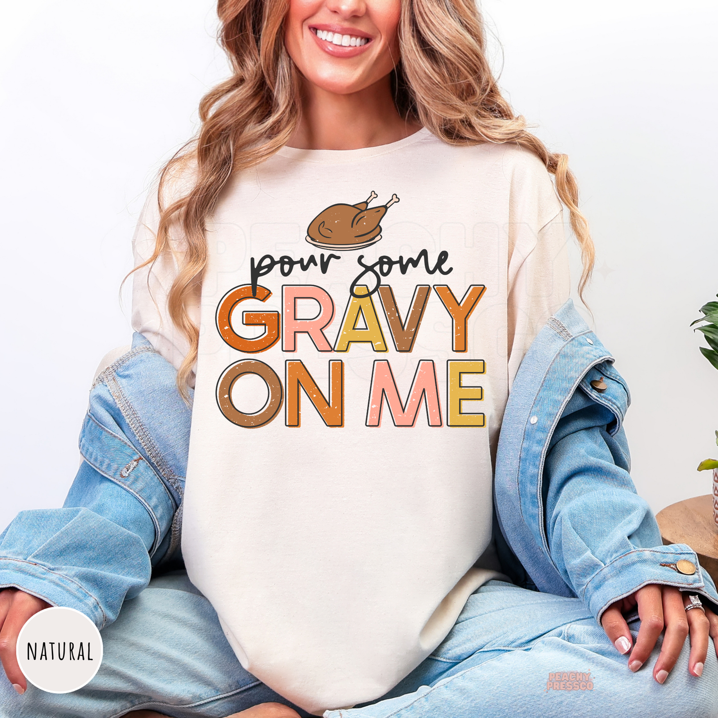 Woman wearing a natural t-shirt featuring a trendy "Pour Some Gravy On Me" Thanksgiving graphic with a roasted turkey and vintage-inspired lettering.