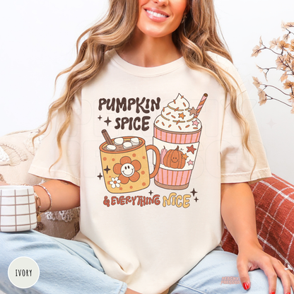 Woman wearing an ivory graphic t-shirt featuring a cute "Pumpkin Spice & Everything Nice" design with a pumpkin spice latte, hot cocoa mug, and whimsical fall coffee artwork, perfect for autumn and cozy coffee lovers.