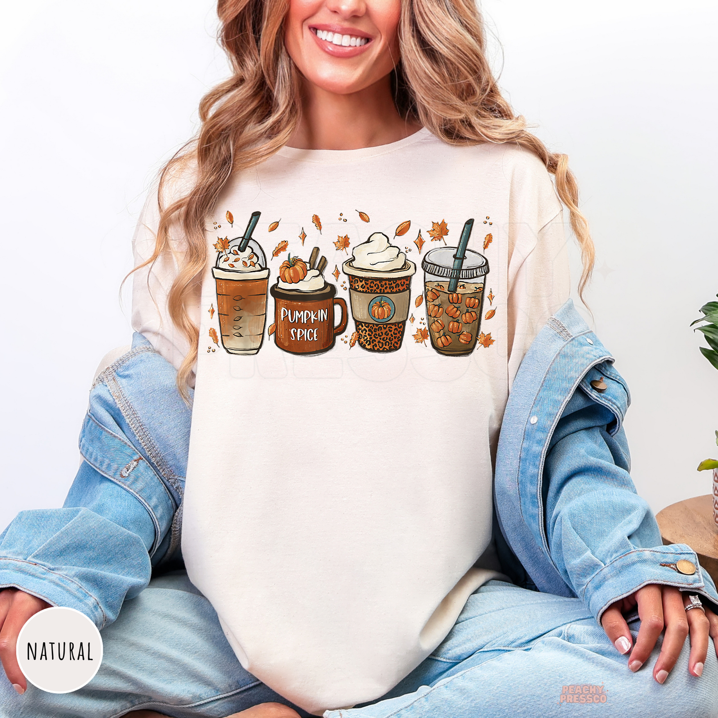 Woman wearing a natural graphic t-shirt featuring a pumpkin spice latte coffee graphic with fall coffee drinks and cozy autumn vibes.