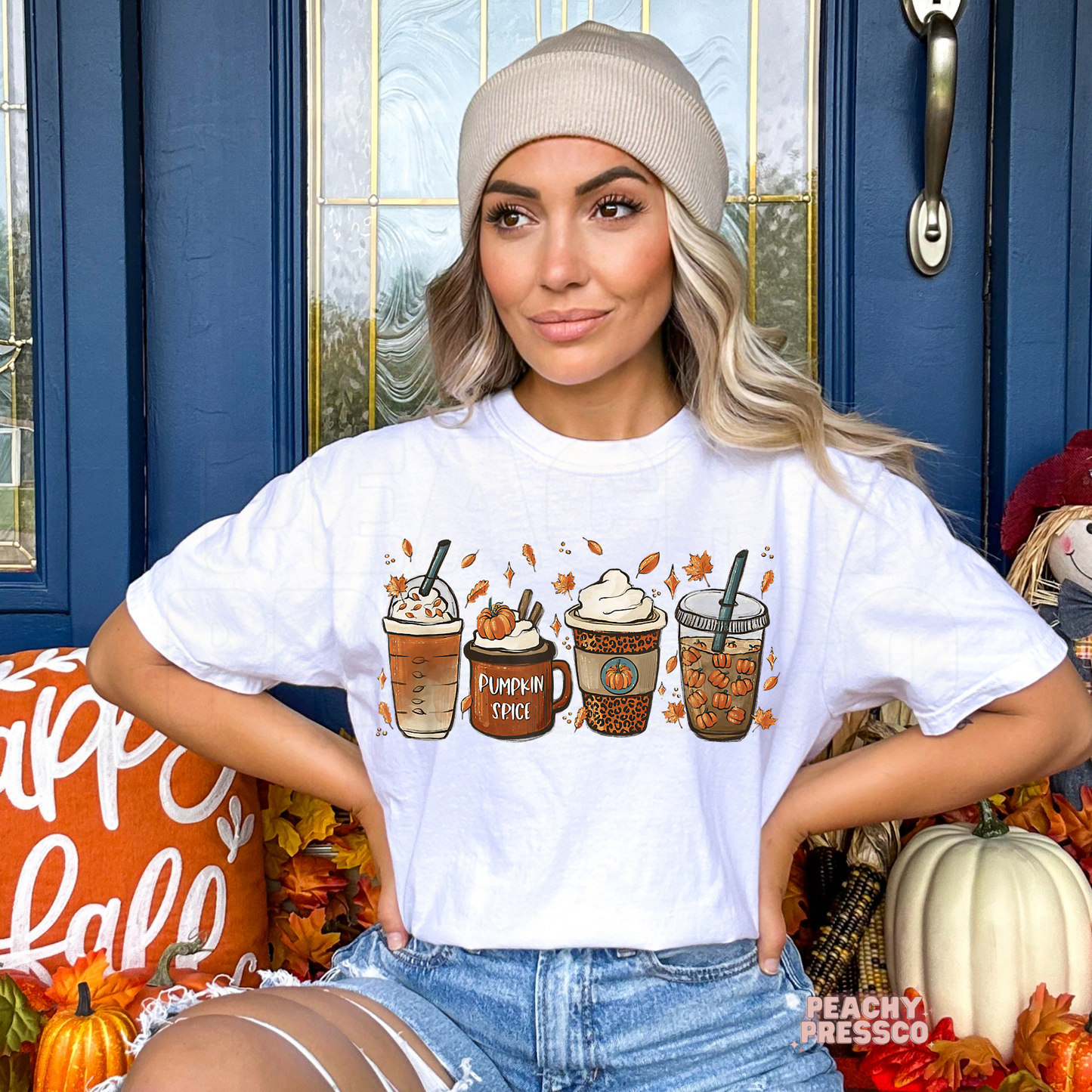 Woman wearing a white graphic t-shirt featuring a pumpkin spice latte coffee graphic with pumpkin drinks, whipped cream, and autumn leaves.
