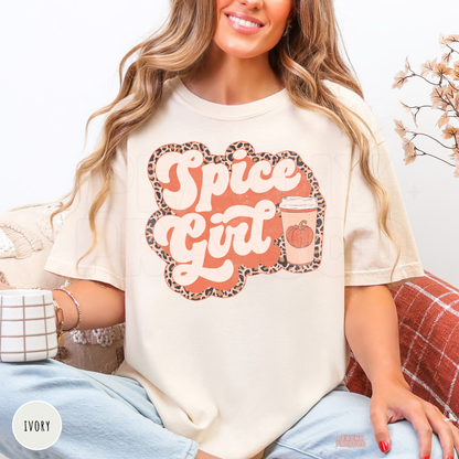 Woman wearing an ivory graphic t-shirt featuring a Pumpkin Spiced Girl design with a pumpkin coffee cup and leopard print border.