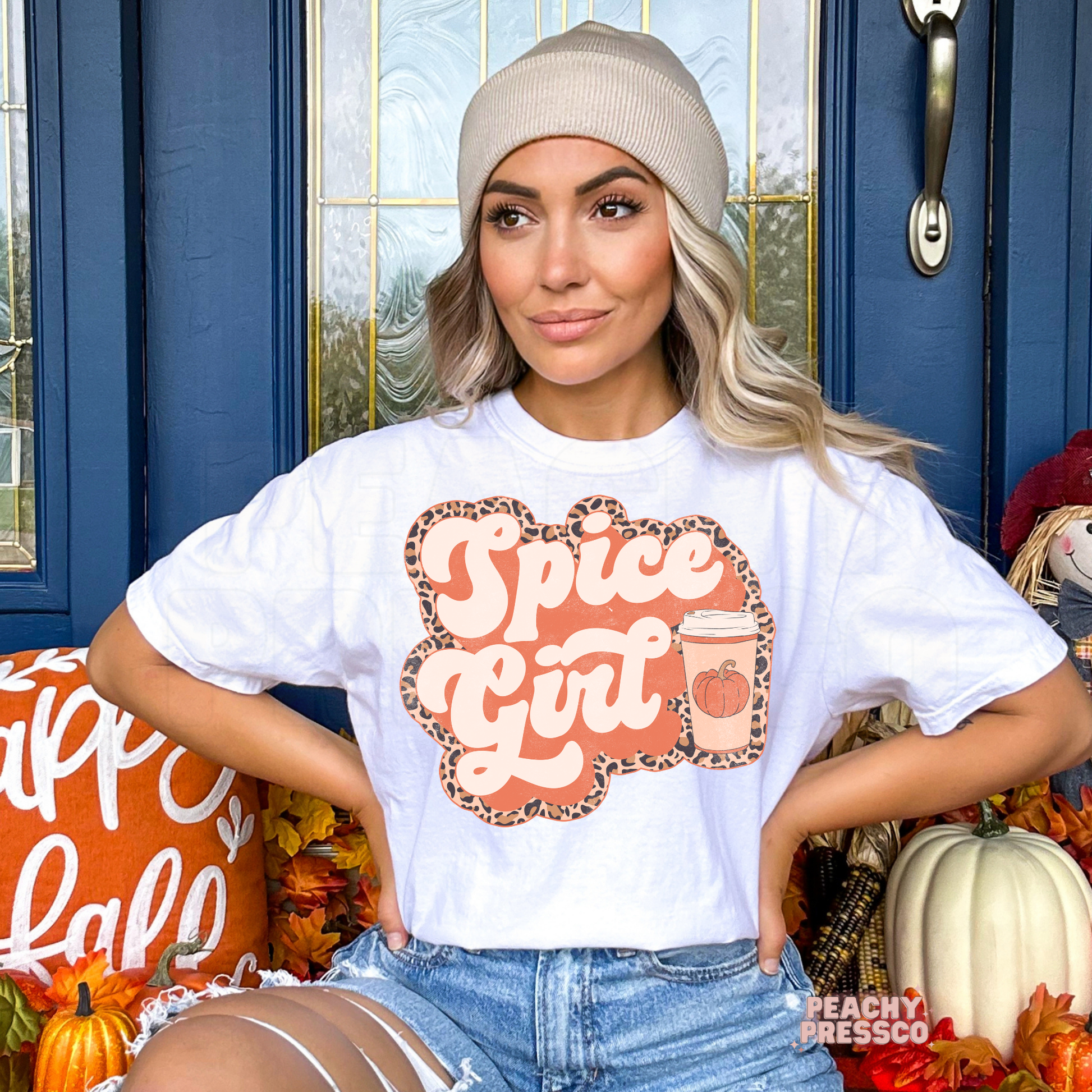 Woman wearing a white graphic t-shirt featuring a Pumpkin Spiced Girl pumpkin coffee design with trendy leopard print accents.