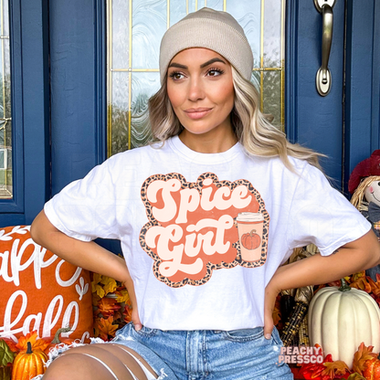 Woman wearing a white graphic t-shirt featuring a Pumpkin Spiced Girl pumpkin coffee design with trendy leopard print accents.
