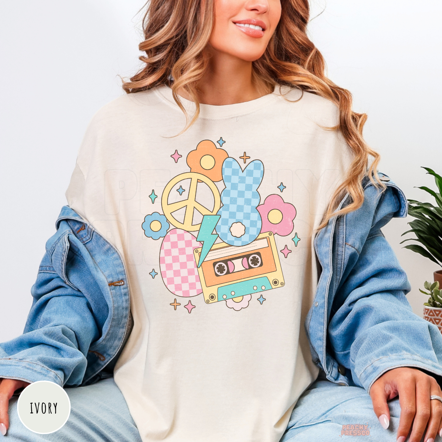 Woman wearing an ivory Comfort Colors t-shirt featuring a retro pastel Easter bunny graphic with a cassette tape, peace sign, flowers, and lightning bolt.