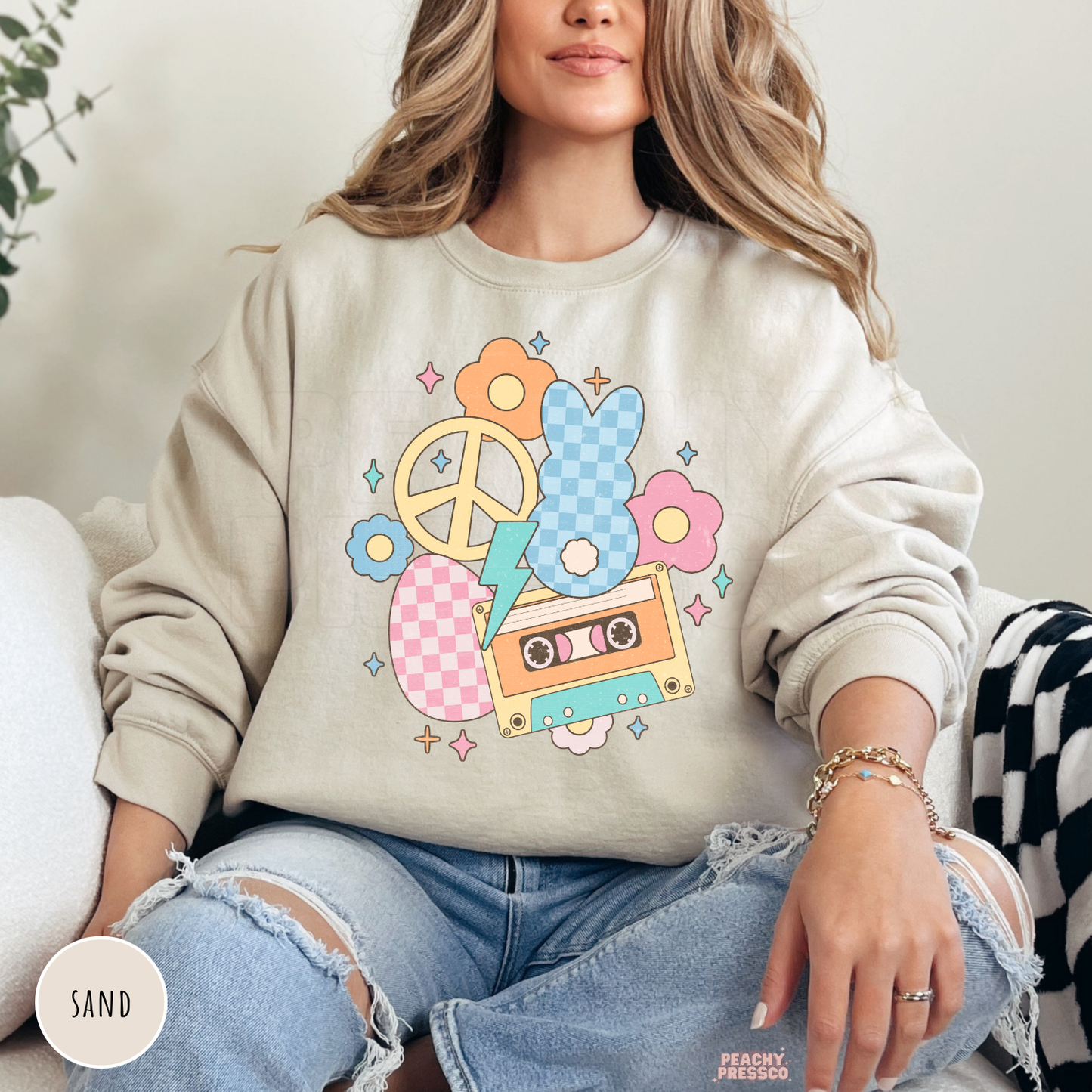 Woman wearing a sand crewneck sweatshirt featuring a vintage pastel Easter bunny graphic with a cassette tape, flowers, peace sign, and lightning bolt.