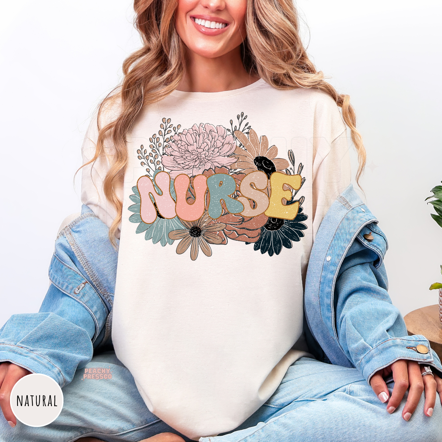 Woman wearing a natural retro floral nurse shirt featuring pastel flowers and colorful "NURSE" lettering.
