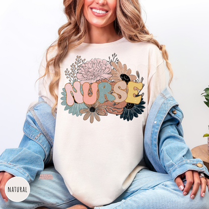 Woman wearing a natural retro floral nurse shirt featuring pastel flowers and colorful "NURSE" lettering.