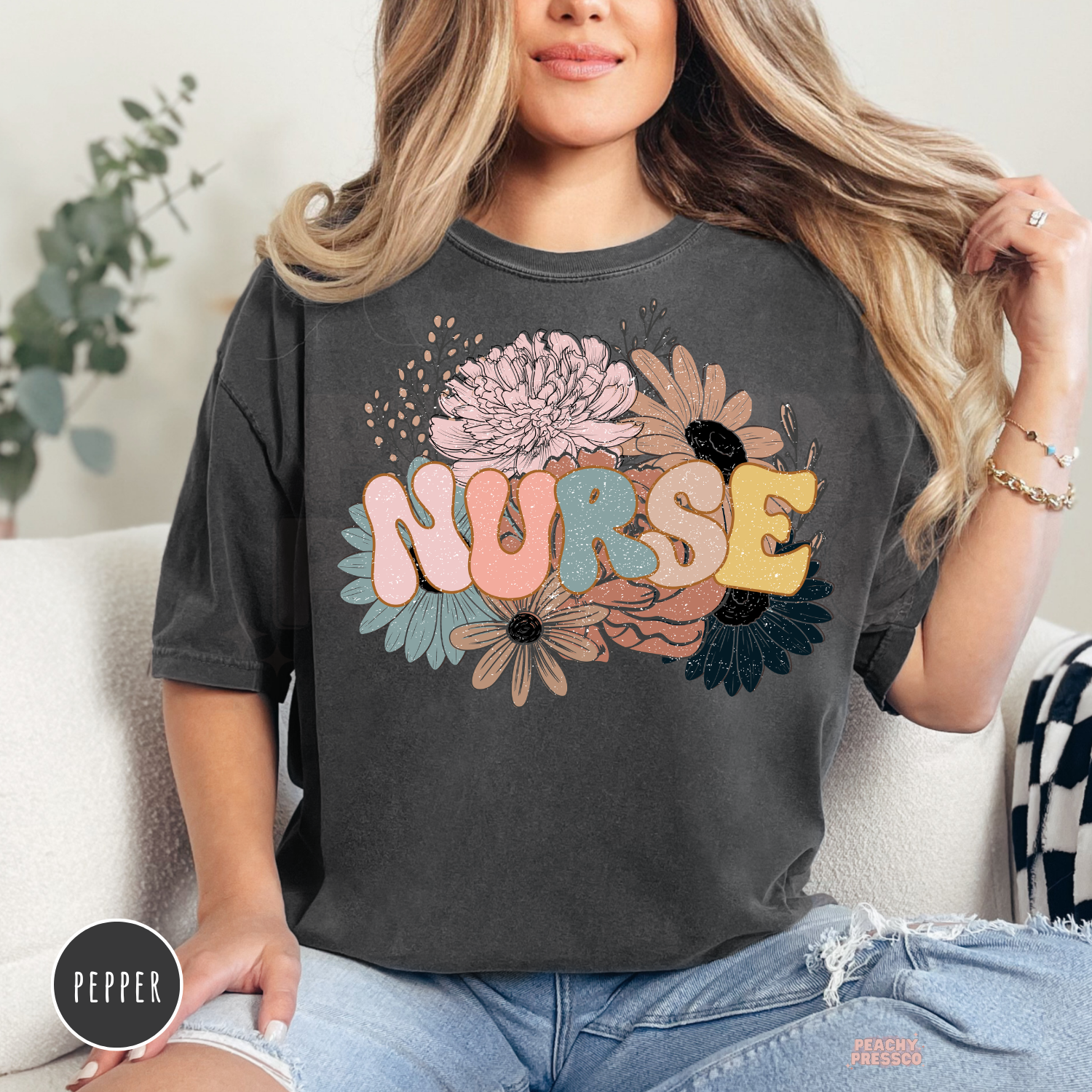 Woman wearing a pepper Comfort Colors retro floral nurse t-shirt with colorful floral nurse graphic.