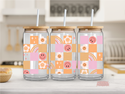 16 oz glass can featuring a retro patchwork design with smiley faces, flowers, rainbows, and sparkles in soft pastel colors.